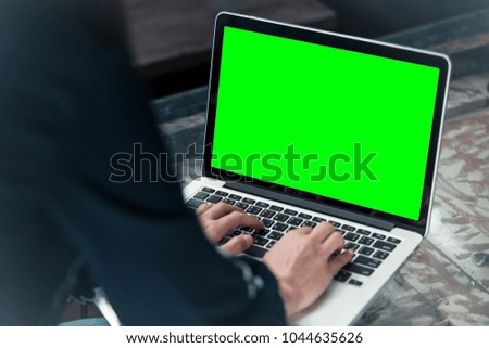 Mockup image of a woman using laptop with blank green screen.