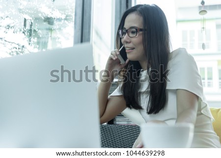 Beautiful asian attractive woman has working and talking with phone for business marketing at coffee cafe in the morning with happy and relaxing time.