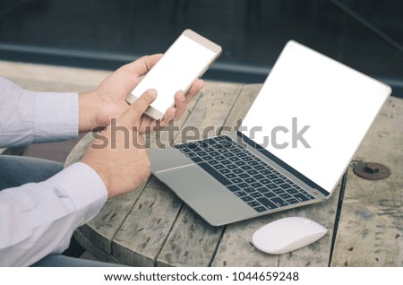 attractive hand of business man using smartphone and laptop working on wood table at outdoor with white screen.