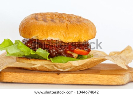 bbq beef burger on white background with fresh greens, souse on wooden plate