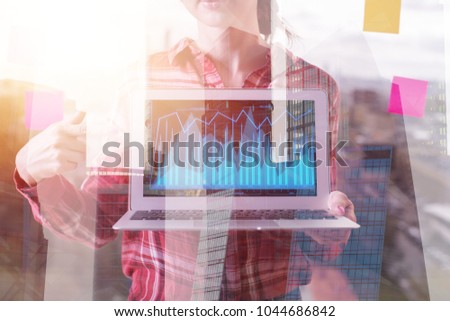 Woman pointing at laptop screen with business chart. Creative city background. Double exposure 