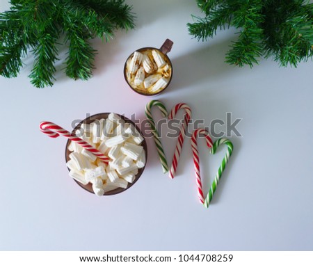 Christmas background, greeting card with a Cup of coffee or hot chocolate with marshmallows, a red plate, candy canes and tree branches. Holiday photo. The mood of the expectations of celebration