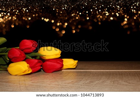 Beautiful red and yellow tulips lie on wooden boards on a shiny background