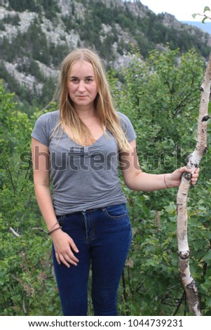 Young beautiful blonde with slender legs and tight jeans posing against the background of the Ural mountains. National Park "Taganay", Russia. Sports tourist in the mountains