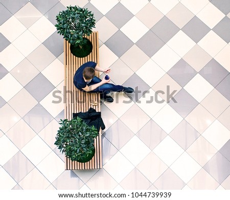 young man biting sitting on the benches, a top view from the supermarket
