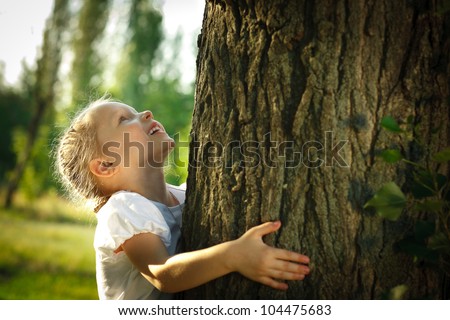 Little girl hugging a tree, looking up Royalty-Free Stock Photo #104475683