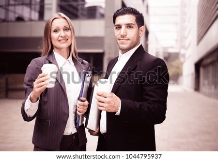 Portrait of couple who are standing with folder and coffee near the office.