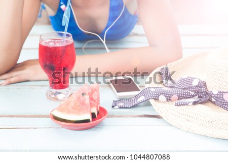 Watermelon and cocktail with woman wears bikini relaxing by smartphone in background, Summer concept 
