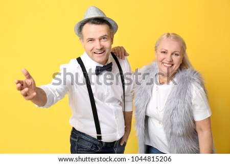 Portrait of stylish pensioners on color background