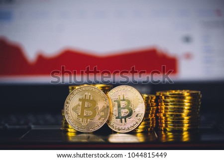 Bitcoin coins pile and two bit coins sitting in front with market crashing and turning red graph chart digital background. Concept of Bitcoin and virtual currency and blockchain technology