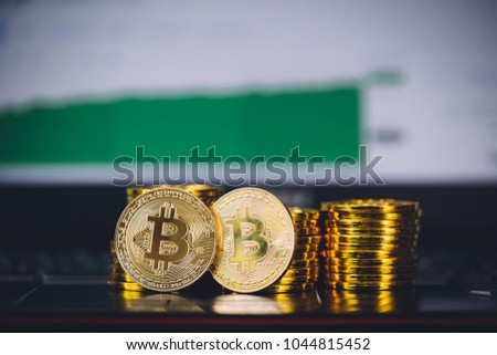 Bitcoin coins pile and two bit coins sitting in front with market spiking and turning green graph chart digital background. Concept of Bitcoin and virtual currency and blockchain technology
