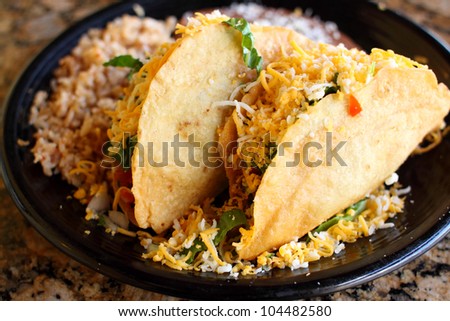 Delicious crunchy tacos with beans and rice at a restaurant.