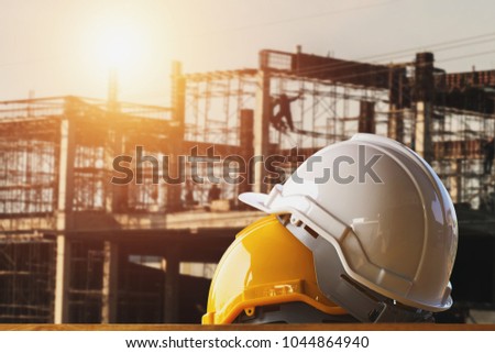 white and yellow safety helmet in construction side with sunset