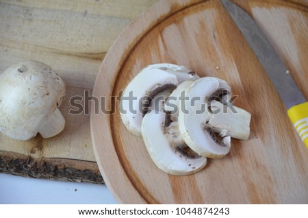 white mushrooms champignons cut on a board. Ready for cooking, frying, pizza, mashed potatoes, salad. Fresh white mushrooms champignon in brown basket on wooden background. Top view. Copy space