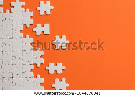 White details of puzzle on orange background. Royalty-Free Stock Photo #1044878041
