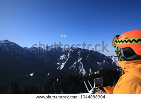 remote controlling a flying drone on winter mountain top