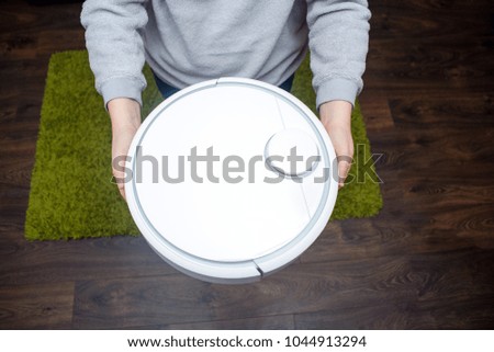 Womans hands holding the vacuum cleaning robot