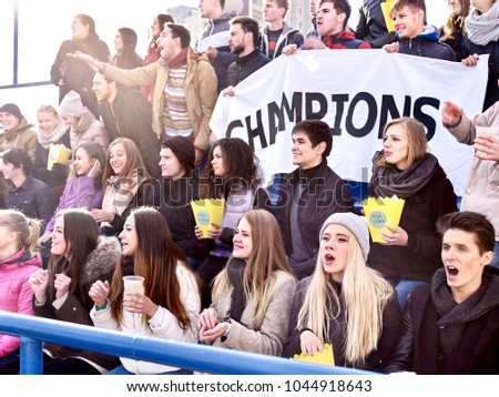 Fans cheering in stadium holding champion banner and singing on tribunes. People are waiting for start of sports competitions. People holding banner with Champion banner happily eating popcorn.