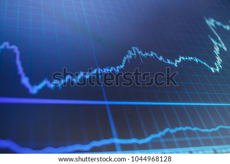 Financial statistic analysis on dark background with growing financial charts. Analysing stock market data on a monitor. A metaphor of international financial consulting. Bitcoin price watch. 