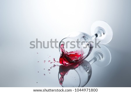 Red wine spilled out of a falling glass with reflection on the surface