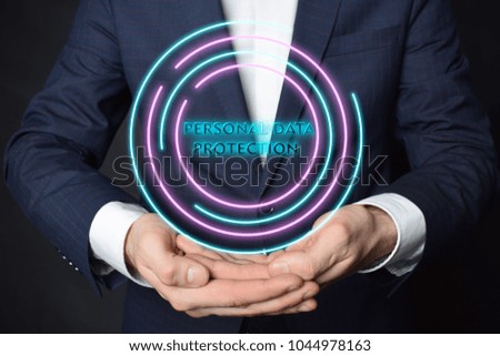 In the hands of a businessman, a neon circle with the inscription:PERSONAL DATA PROTECTION