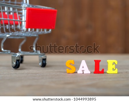 Colorful wooden word SALE on wooden table and shopping cart and background wooden. English alphabet made of wooden letter color. The concept of shopping and Discount festival