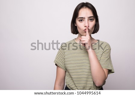 Young beautiful girl looking at camera showing keep silence over gray background.