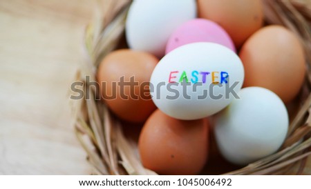 Many pink, white and orange eggs are in the straw basket and put it on the wooden table. The picture concepts for Easter, natural, painting, food, ingredient, healthy, right.