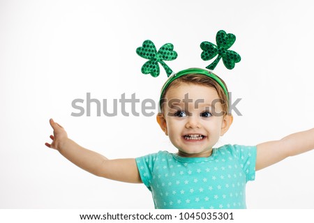 St.Patrick's day clover head decoration on a close up of an excited toddler girl	