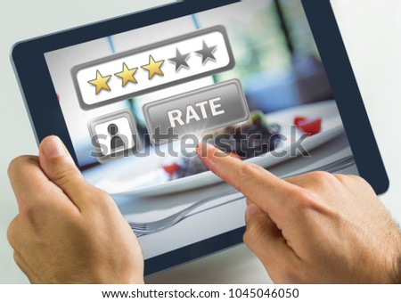Digital composite of Hand touching tablet with Rate button and review stars in restaurant with dinner food