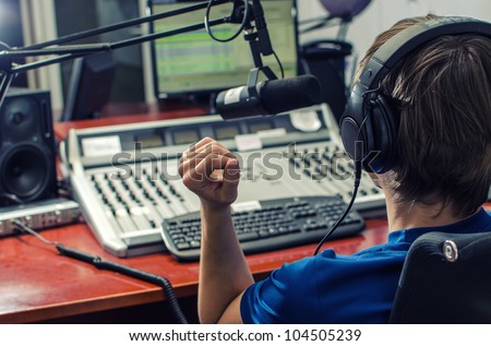 Dj working in front of a microphone on the radio, from the back Royalty-Free Stock Photo #104505239