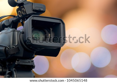 Front view of video camera with  bokeh light in background, Selective focus. Royalty-Free Stock Photo #1045065148