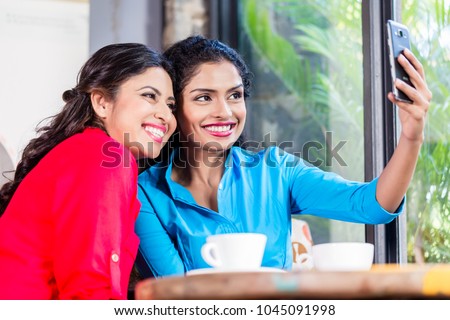 Customers in Indian cafe taking selfie, view through shop window