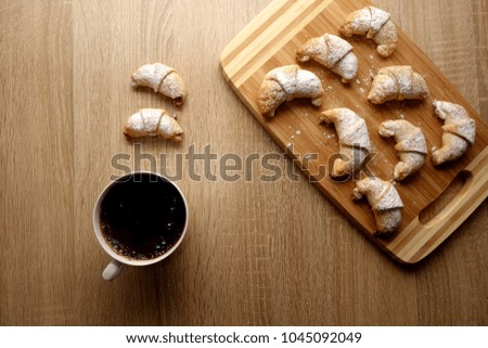 Little croissants and cup of coffee on rustic table background, copy space for text or object