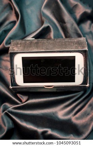 Close up of an Un -boxed digital smart phone in its box on a dark shiny surface.