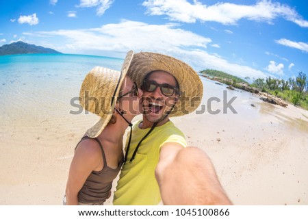 Happy caucasian couple in love taking a selfie at a tropical beach in holiday