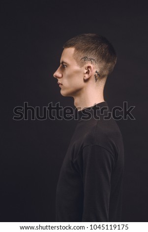 Side view of man with tattoo on temple isolated on black