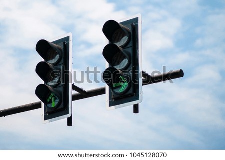 Green traffic light green direction light against soft blue sky background