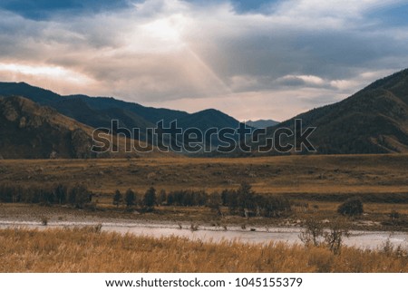The ray of the sun makes its way through the clouds. Mountains and hills. The Katun River.