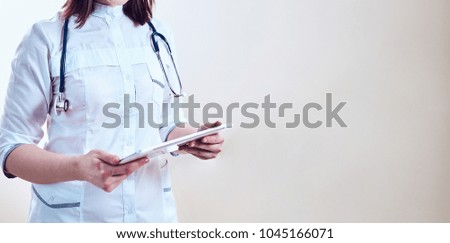 Woman doctor with tablet at the office, text messaging.