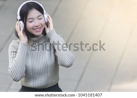 Pretty asian girl listening music with her headphones on the street, Happiness time concept