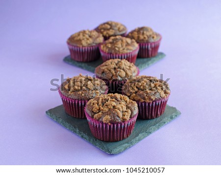 Chocolate muffins on black square board on purple background