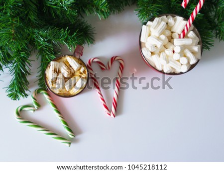 Christmas background, greeting card with a Cup of coffee or hot chocolate with marshmallows, a red plate, candy canes and tree branches. Holiday photo. The mood of the expectations of celebration