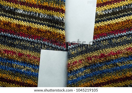 Colorful Knit Fabric Texture with White Card of Paper as Blank Space. Macro View of a Knitted Sweater. Blank Backdrop Mock-Up