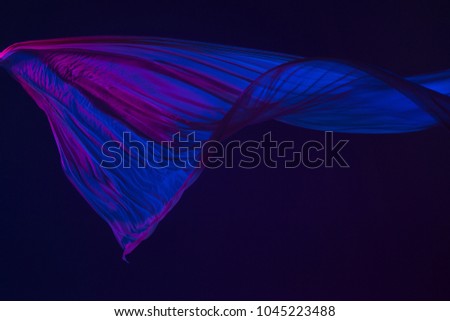 Smooth elegant transparent blue cloth isolated or separated on dark blue studio background. Texture of flying silk fabric.
