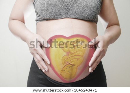 Pregnant woman with painted Cartoon embryonic unborn child on her stomach,Use computer graphics techniques, like coloring posters. Concept of Health Care During Pregnancy.