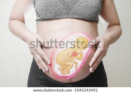 Pregnant woman with painted Cartoon embryonic unborn child on her stomach,Use computer graphics techniques, like coloring posters. Concept of Health Care the brain and heart During Pregnancy.