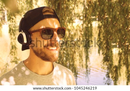 Cheerful man listening to music in headphones outdoors                   