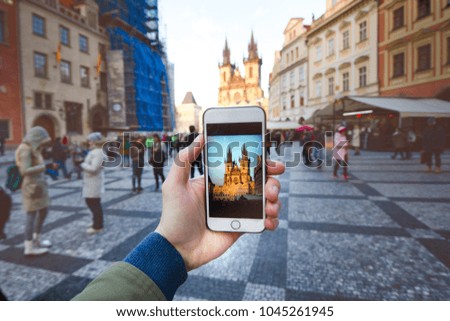 Photo camera of smartphone and old Prague centre with famous sightseeing. Old city square with people during the sunset