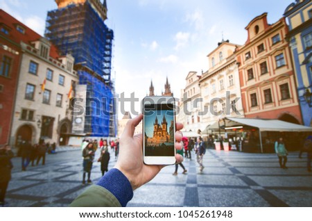 Photo camera of smartphone and old Prague centre with famous sightseeing. Old city square with people during the sunset